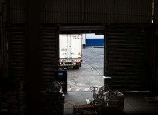 Ciężarówka dostawcza wyjeżdża z półmrocznego magazynu cross-dock