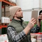 Traceability w logistyce hurtowej: jak śledzić partię od dostawcy do klienta Pracownik magazynu skanuje towar skanerem ręcznym między regałami