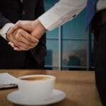 Kiedy outsourcing logistyki B2B się opłaca, a kiedy lepiej zostać przy in-house Dwóch specjalistów B2B podaje sobie ręce na tle panoramy miasta